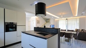 Una cocina moderna con una isla central, horno integrado y un área de comedor con sofá y sillas.