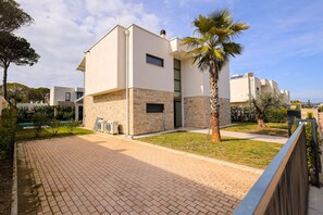 A modern building with a flat roof, a stone base, and a small window.