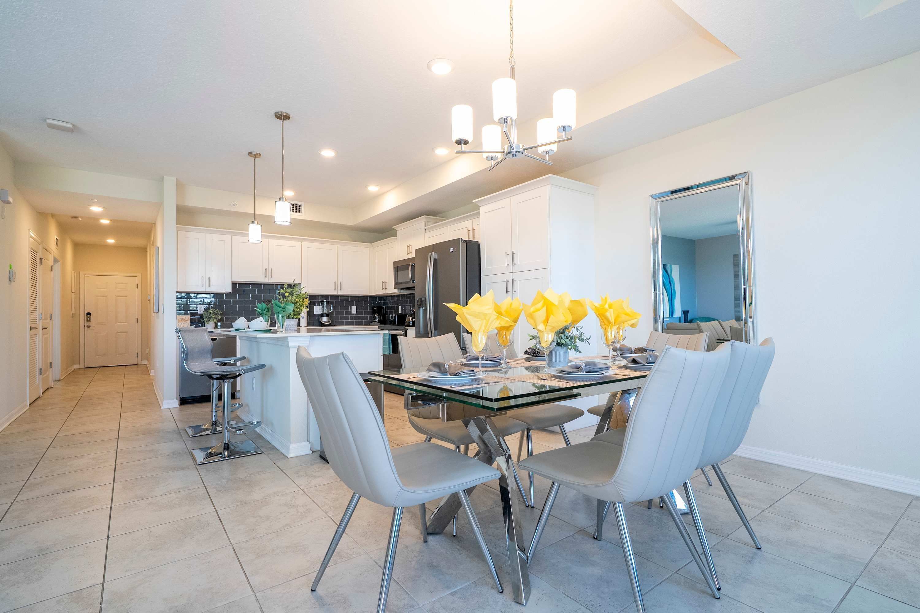 A modern kitchen with white cabinets, stainless steel appliances, and a glass dining table with chairs.