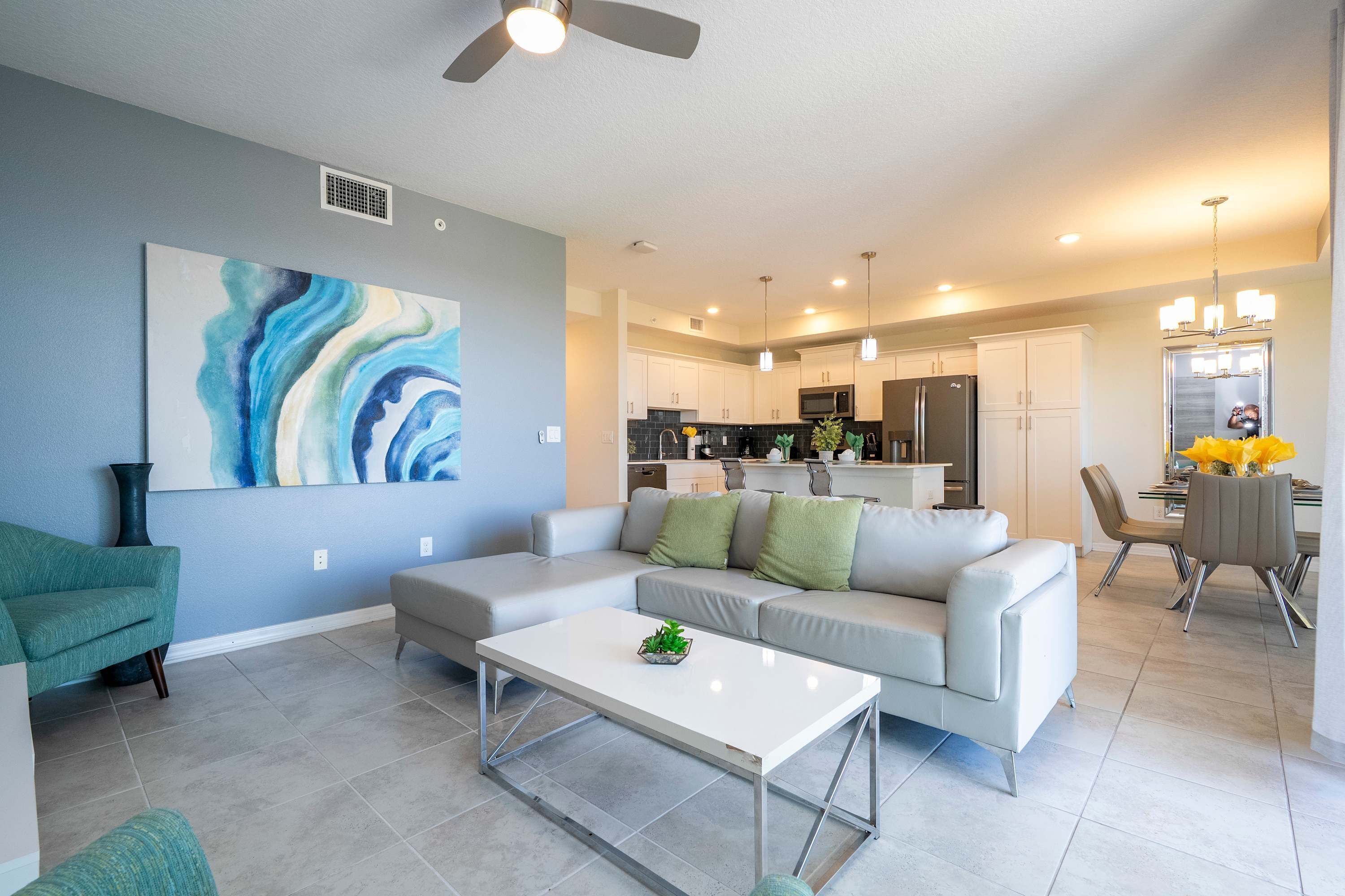 A modern living room with a white sofa, a coffee table, and a painting on the wall.