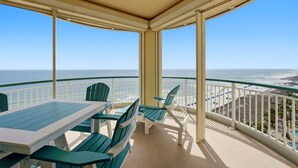 A balcony with a table and chairs, overlooking a beach and ocean. - Welcome to the Beach Colony West 11C (Perdido Key)