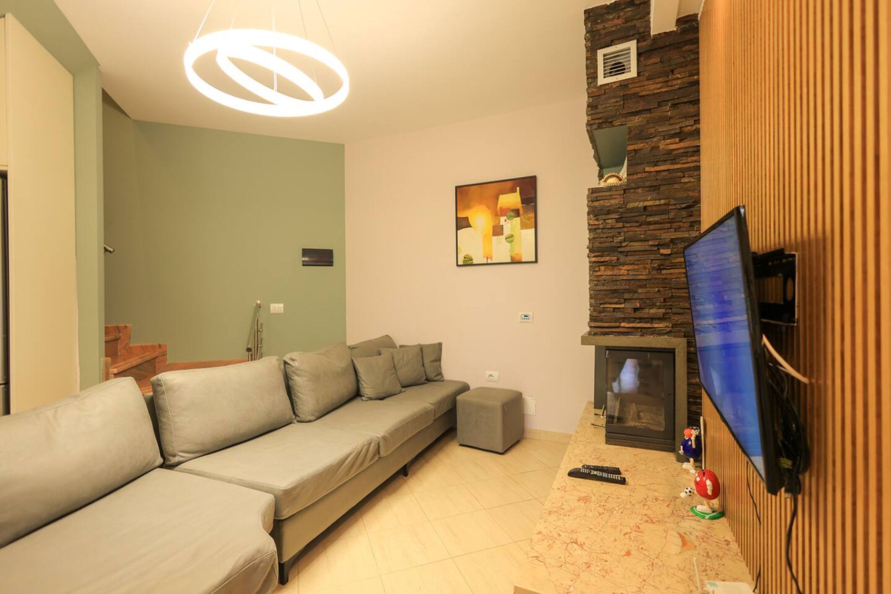 Una sala de estar con sofá, chimenea, televisión y una pared de acento de piedra.