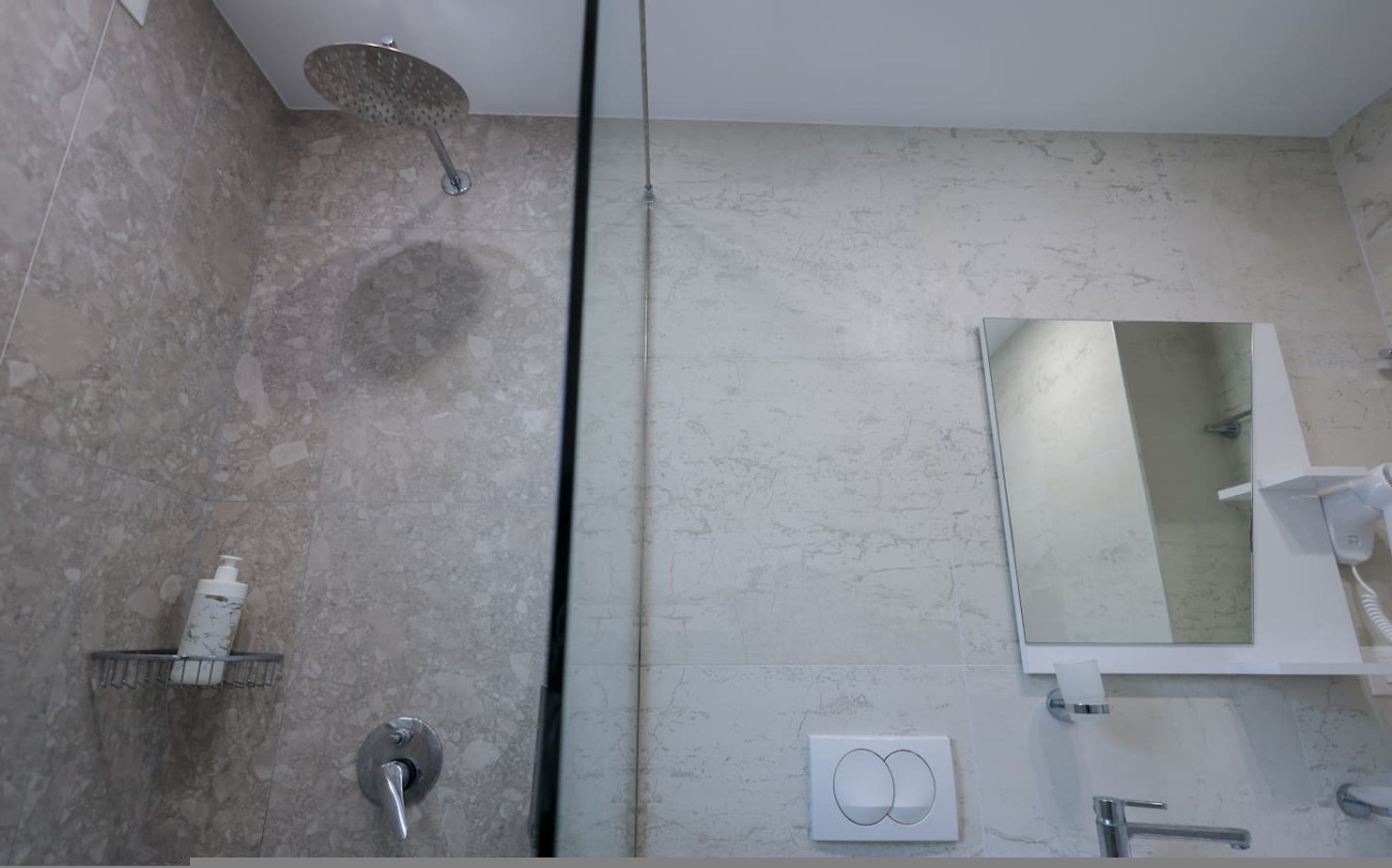 Uma casa de banho moderna com chuveiro, sanita e lavatório.