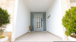 A modern entrance with a glass door, potted plants, and a clean tiled floor. - Beach Apartment 01 in Durrës (Durrës)