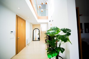 A modern hallway with a wooden door, a staircase, and a large plant. - Villa Apollon:  Seaside and luxurious (Marsa)