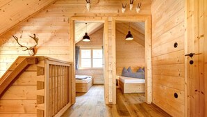 A log cabin interior with a loft bedroom, a staircase, and a window. - CASALPIN Chalets (Brand)