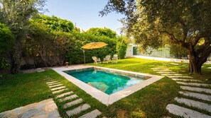 A rectangular swimming pool with a stone border, surrounded by a well-maintained lawn and a variety of trees. - Residence Jannet 2 Luxury Seaside 3 bedrooms (Mrezga)