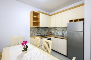 Eine moderne Küche mit weißen Schränken, einer Marmor-Spritzschutzwand und einem Edelstahl-Kühlschrank.