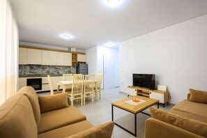 Una sala moderna con un sofá, una mesa de centro de madera y un televisor.