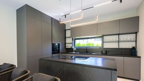 A modern kitchen with a central island, built-in appliances, and a window overlooking greenery.