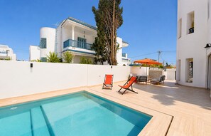 A swimming pool with lounge chairs and a building in the background. - Villa Ambre : détente, piscine privée & hammam (La Marsa)
