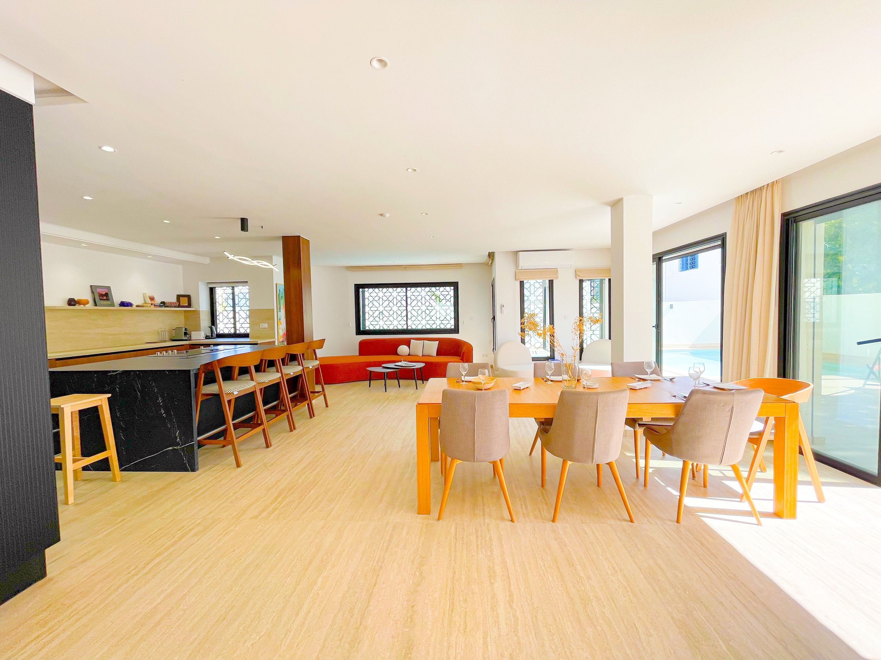 Una sala moderna con comedor, cocina y ventanas amplias.