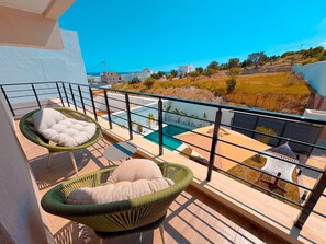 A balcony with two wicker chairs, a small table, and a pool. - villa Alba: luxe et confort a Hammamet (Mrezga)