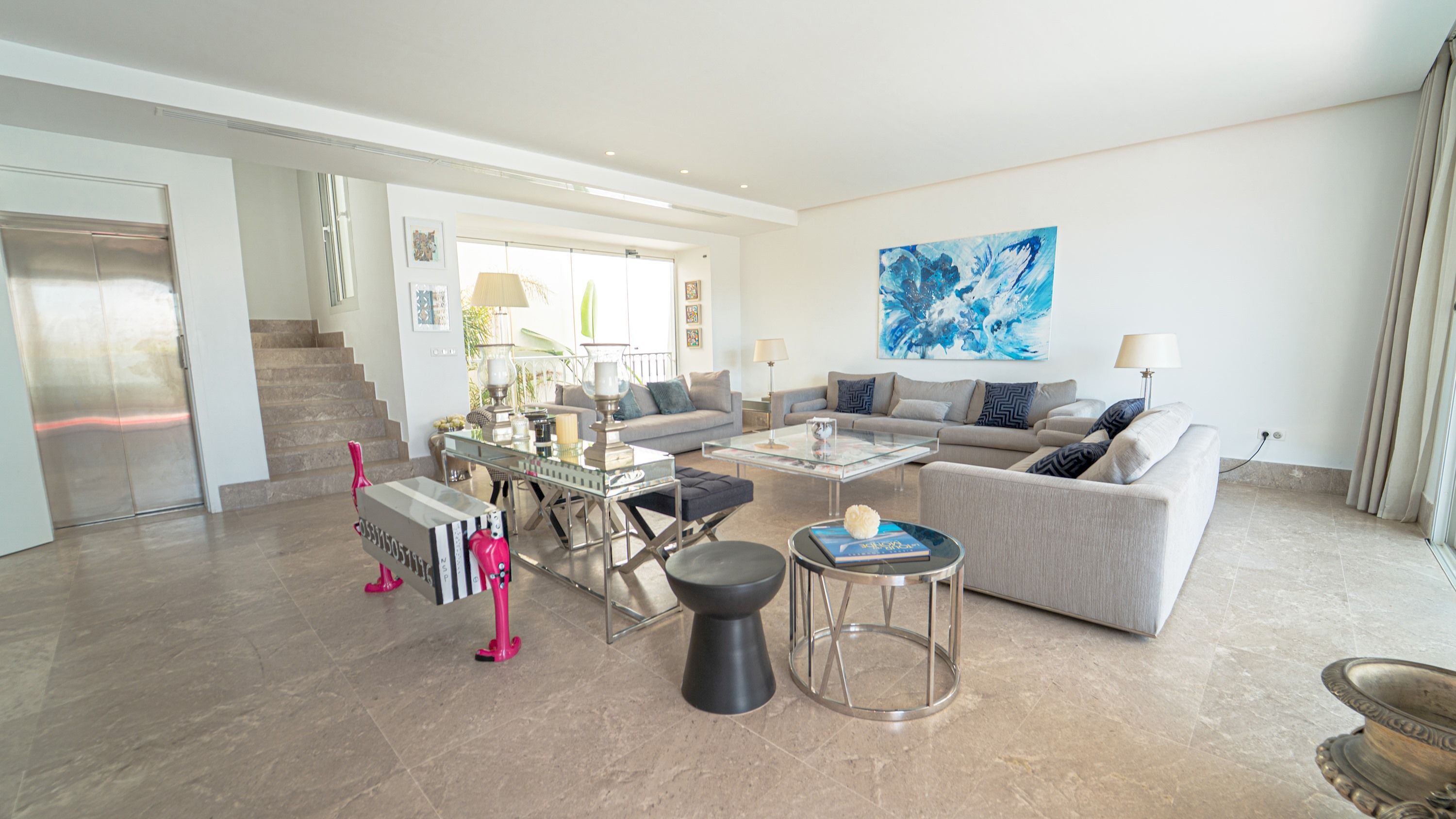 Ein großzügiger Wohnraum im modernen Stil mit einem großen Sofa, einem Couchtisch sowie einem Essbereich mit Glastisch und Stühlen.