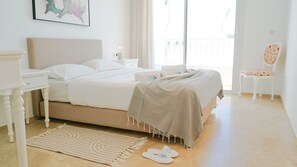 Ein Schlafzimmer mit einem Bett, Nachttischen, einem Sessel und Blick ins Freie.