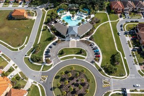 An aerial view of a residential area with a central roundabout, a swimming pool, and surrounding houses. - Family Friendly 12Bd w Jacuzzi Veranda Palms 4401 (Kissimmee)