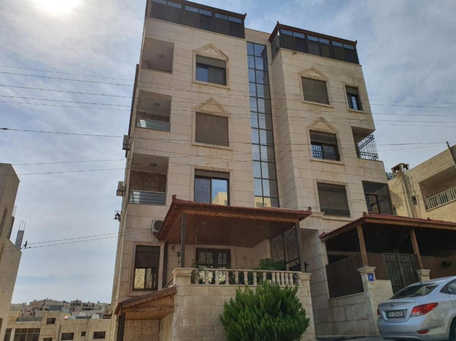 Un edificio a più piani con facciata piatta e diversi balconi, con un'auto parcheggiata davanti.