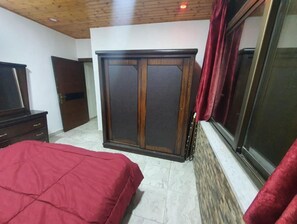 A bedroom with a bed, wardrobe, and a window with curtains.