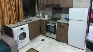 Uma cozinha compacta com máquina de lavar, fogão, forno e geladeira.