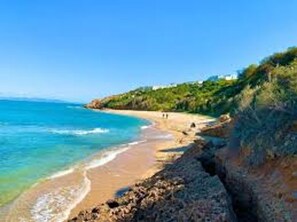 A coastal beach with clear blue waters, a sandy shore, and rocky cliffs. - La Marina: secure seaside with pool (La Marsa)