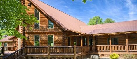 A log cabin with a porch, a staircase, and a well-maintained lawn.