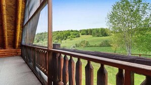 A wooden cabin with a balcony overlooking a green landscape. - Luxurious 4-bedroom cabin that sleeps 13 close to Cooperstown NY with AC (Burlington Flats)
