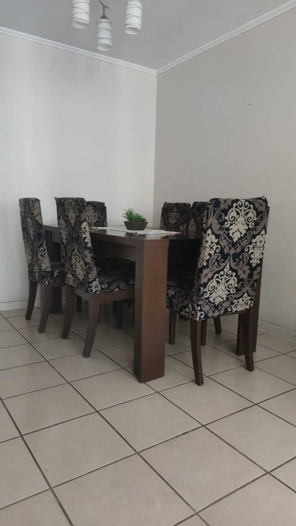 Un comedor con una mesa rectangular rodeada por cuatro sillas con tapicería estampada.