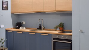 Eine moderne Küche mit blauen Schränken, einer Holzauskładung, einem eingebauten Backofen und einem kleinen Spülbecken.