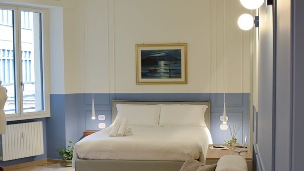Ein Schlafzimmer mit einem Bett, einer Couch, einer Topfpflanze und einem Bild an der Wand.