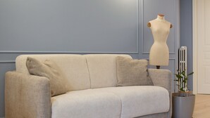 Ein beiges Sofa mit Kissen in einem Raum mit blauer Wand und Heizkörper.