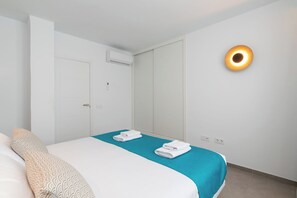 Habitació d'hotel amb llit, porta de bany, unitat de aire condicionat i llum penjada a la paret.