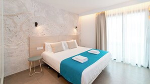 Ein modernes Hotelzimmer mit einem großen Bett, einem kleinen Nachttisch, einer Wandleuchte und einem Fenster mit Vorhängen.