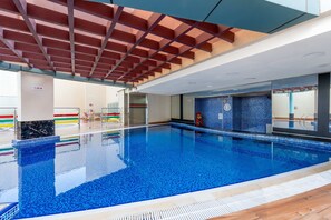 An indoor swimming pool with a tiled floor and a ceiling with a grid pattern. - Free Housekeeping Visits During Your Stay - Stayshort - Cozy 1BR Retreat in JLT That Sleeps 4 (Dubai)