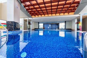 An indoor swimming pool with a tiled floor and a wooden ceiling structure. - Free Housekeeping Visits During Your Stay - Stayshort - Cozy 1BR Retreat in JLT That Sleeps 4 (Dubai)