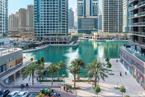 A modern urban area with a central water feature surrounded by palm trees, high-rise buildings, and a pedestrian walkway. - Free Housekeeping Visits During Your Stay - Stayshort - Cozy 1BR Retreat in JLT That Sleeps 4 (Dubai)