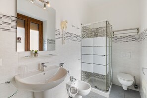 Ein modernes Badezimmer mit einem großen Waschbecken, einem Bidet, einer Duschkabine und einer Toilette.