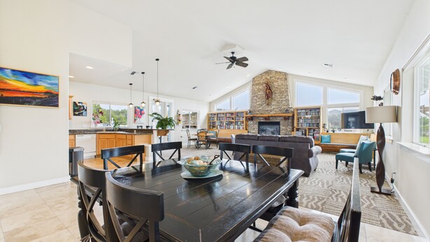 A spacious living area with a dark wooden dining table, comfortable seating, and a stone fireplace. - NEW! Pool, BBQ, Beach Access, Hot Tub, Gym (SDreaming) (Westport)
