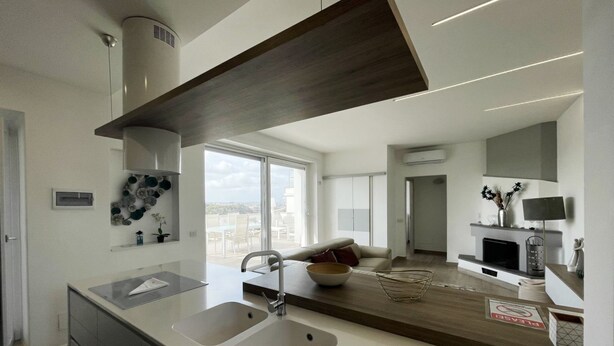 A modern kitchen with two sinks, a wooden countertop, and a view of the city. - Attico con splendida vista su Villa Ada (Roma (RM))