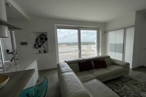 Ein modernes Wohnzimmer mit Sofa, Essbereich mit Tisch und Stühlen sowie Blick ins Freie.