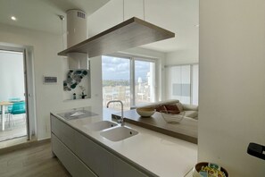 Eine moderne Küche mit einer zentralen Kochinsel, zwei Spülen und einem großen Fenster mit Blick auf die Stadt.
