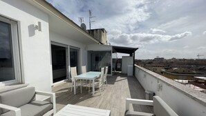A rooftop terrace with a table and chairs, a sofa, and a view of the cityscape. - Attico con splendida vista su Villa Ada (Roma (RM))