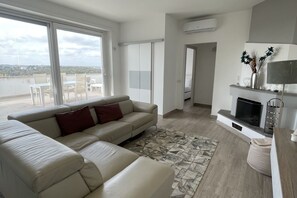 Ein modernes Wohnzimmer mit einem beigen Sofa, einem gemusterten Teppich und einem Kamin.