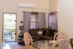 A living room with a glass coffee table, a sofa, and a dining table with chairs. - 3 King Beds Drax Hall~Pool~Gym~Gated~Full Air Con (Draxhall)