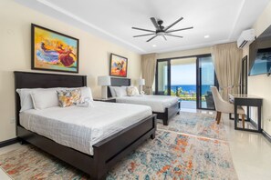 A hotel room with two beds, a ceiling fan, a TV, and a balcony with a view. - Ocean's Edge ~ Fully Staffed ~ Luxury Villa (Tower Isle)