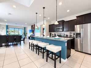 A modern kitchen with a central island, dark cabinetry, stainless steel appliances, and pendant lighting. - Family Villa in Windsor • Lazy River • BBQ • Pool (Kissimmee)