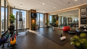 A gym with exercise equipment, a black mat, and a city view. - Midtown Atlanta 1BR Skyline Balcony Corner Condo by Piedmont Park | Luxe Pad (Atlanta)