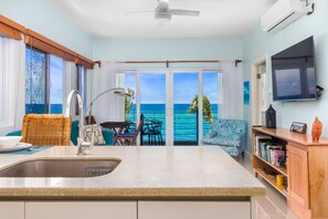 A kitchen with a sink, dining area, and a view of the ocean. - Teal Horizon~OceanfrontCaribbean Escape~Tower Isle (Tower Isle)