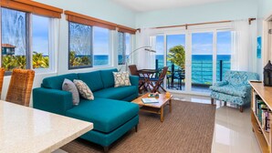 A spacious living room with a teal sofa, a wooden coffee table, and a view of the ocean through large windows. - Teal Horizon~OceanfrontCaribbean Escape~Tower Isle (Tower Isle)