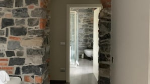 A hallway with a stone archway leading to a bathroom. - Romantic Chic Apartment (Como)