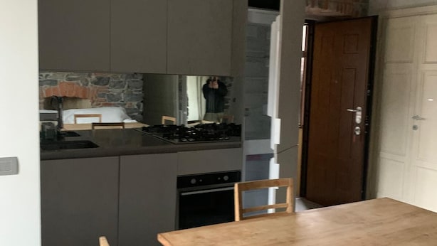 A compact kitchen with a dining area, including a wooden table and chairs, a stove, and a sink. - Romantic Chic Apartment (Como)